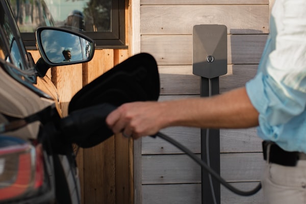 Homeowner plugging in electric vehicle at home charging station